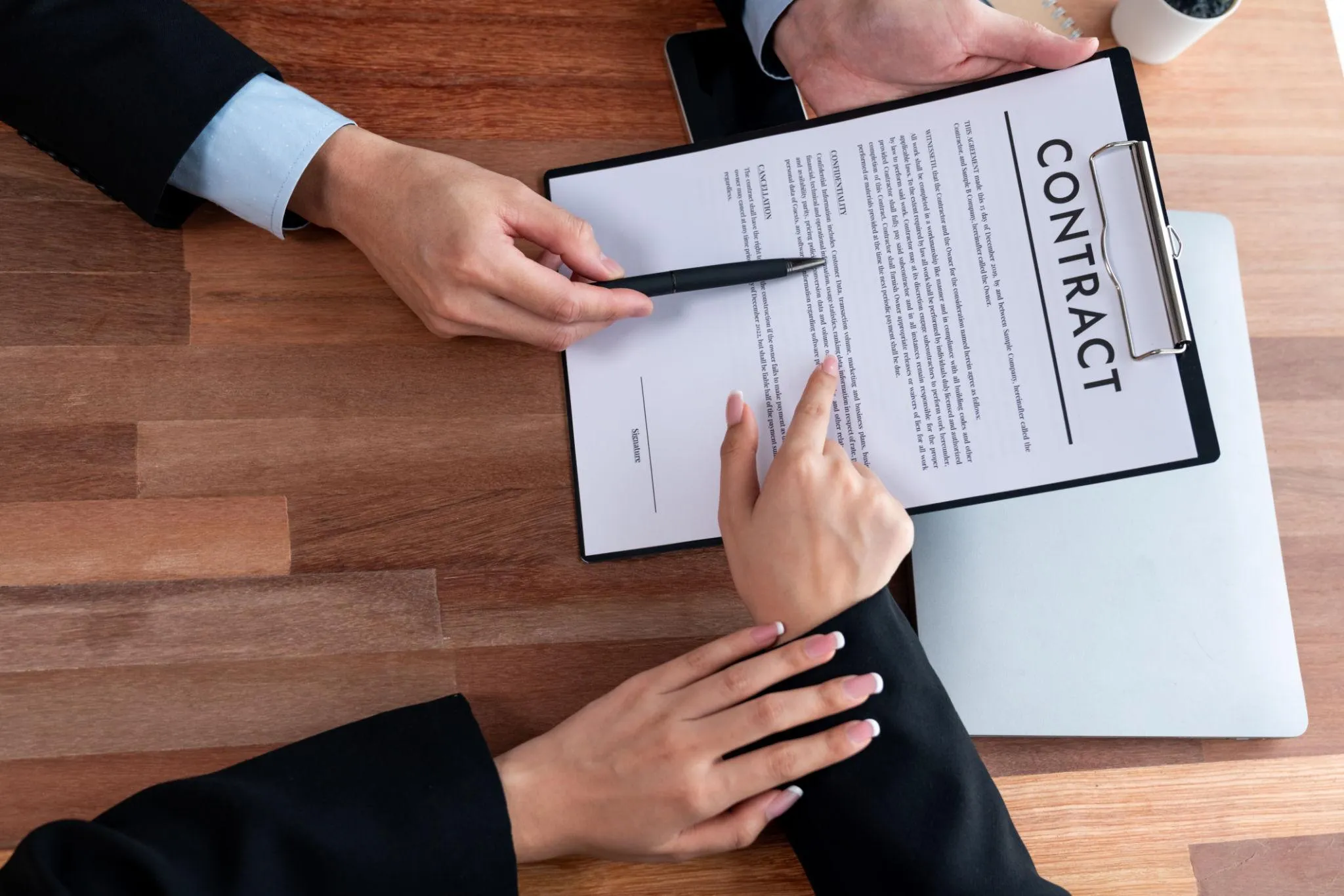 Founder and agency project manager reviewing a printed web app design contract at a wooden desk